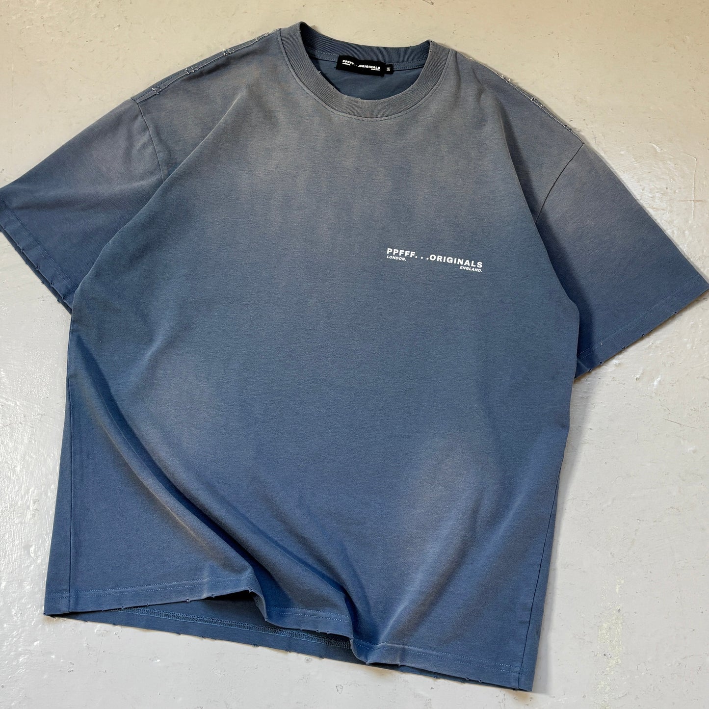 Blue t-shirt with a logo on a light gray surface