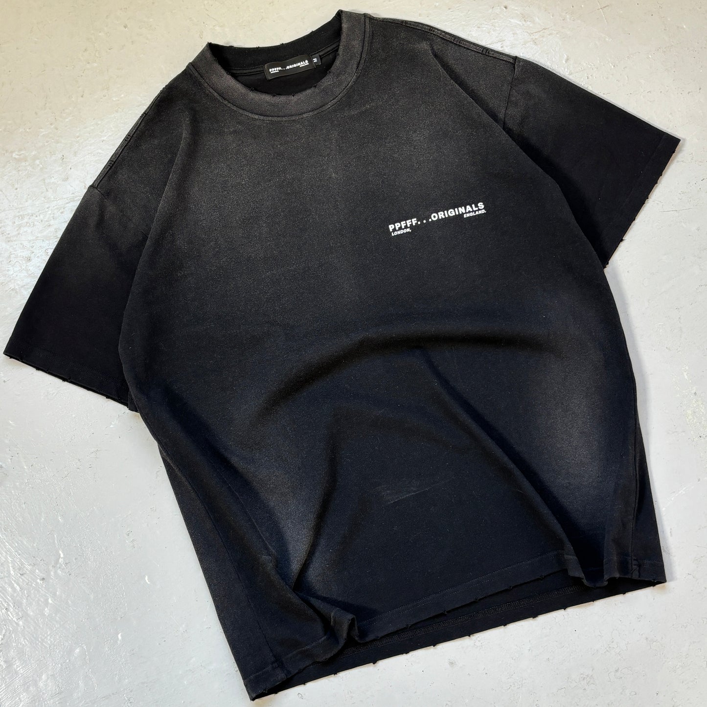 Black t-shirt with a logo on a light gray surface