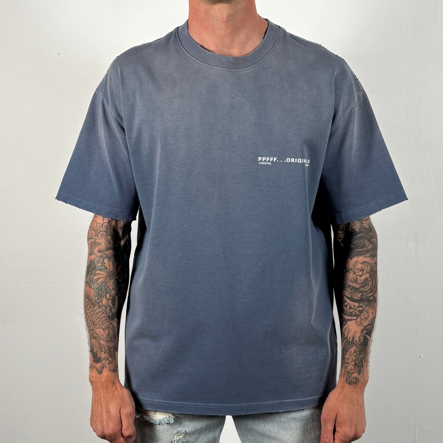Person wearing a gray t-shirt with a logo on a plain background