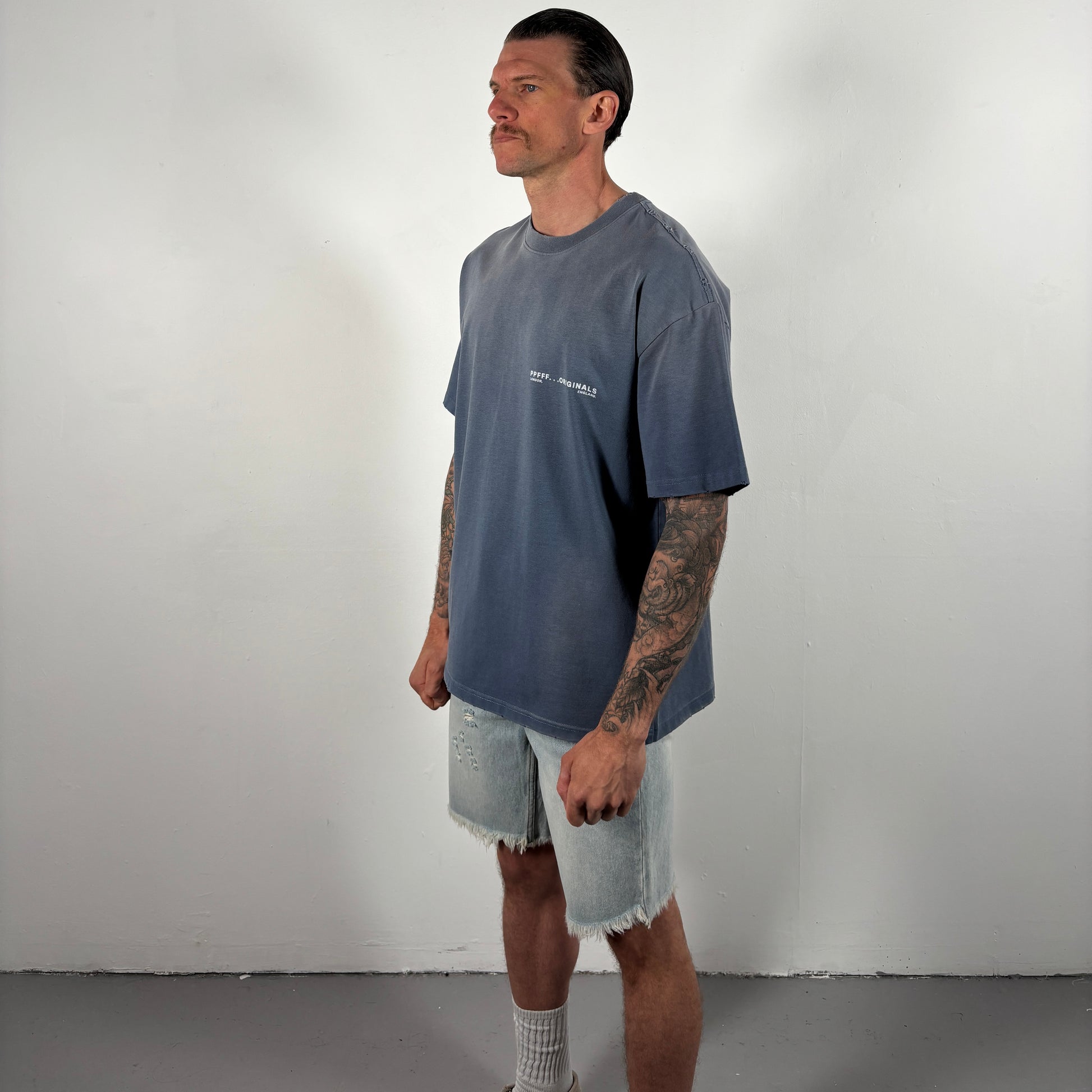 Man wearing a gray t-shirt and denim shorts against a plain background