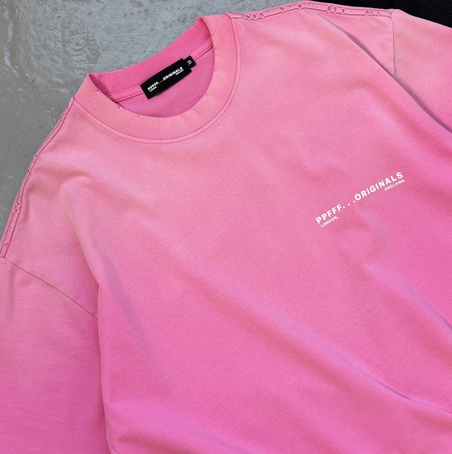 Pink shirt with a brand logo on a textured surface