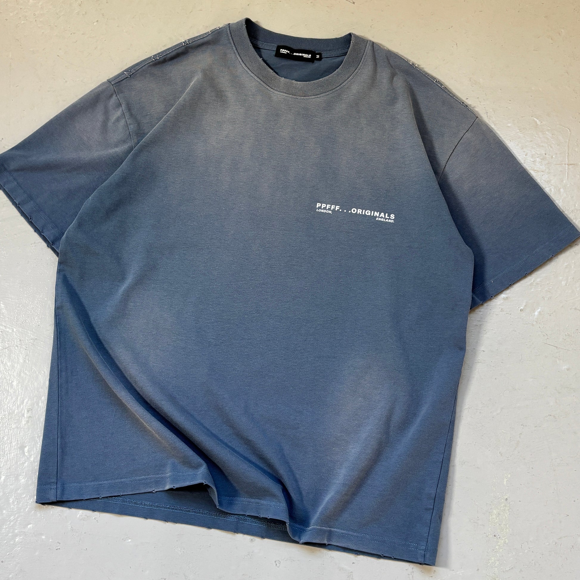 Blue t-shirt with a logo on a light gray surface