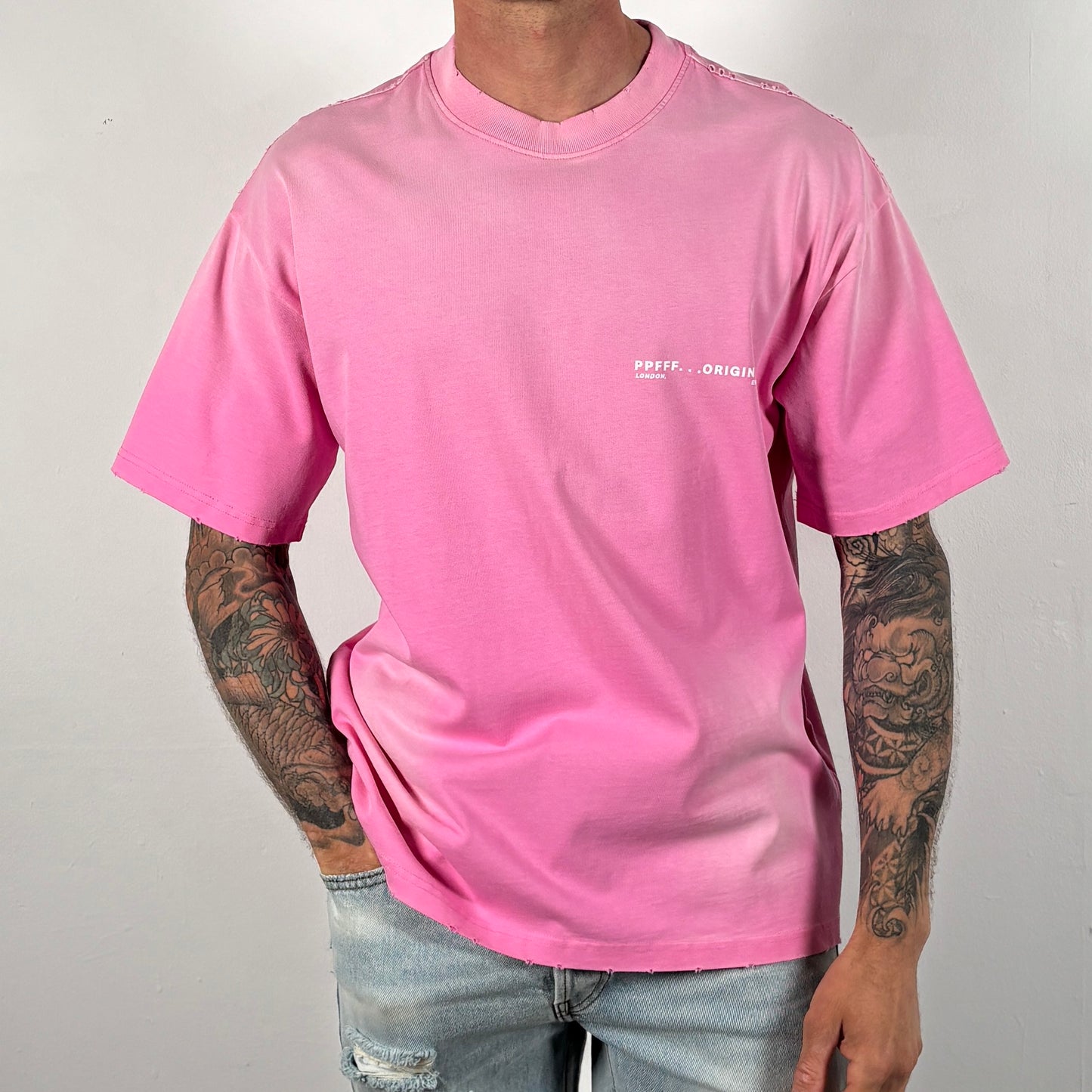 Person wearing a pink t-shirt with a logo on a plain background