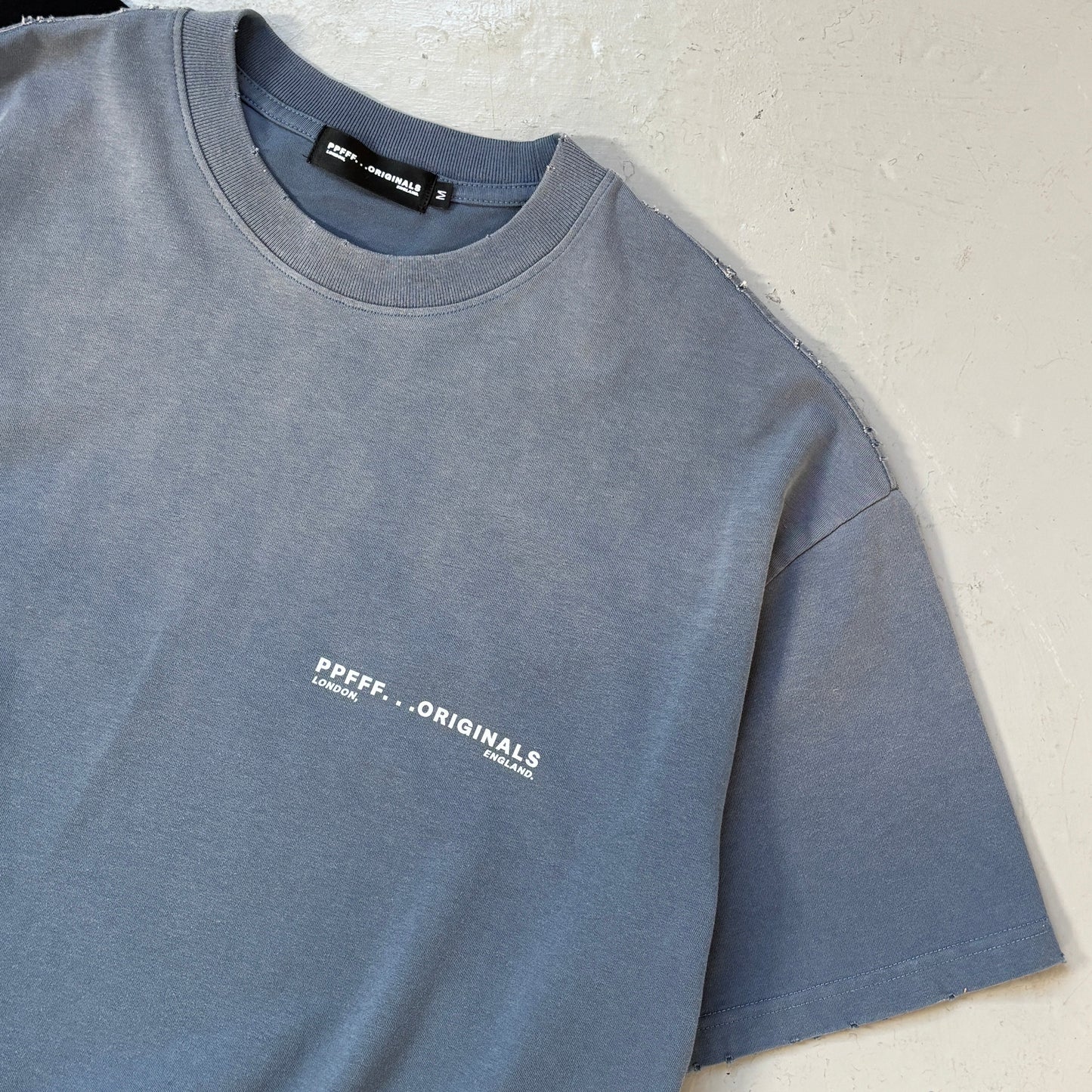 Folded blue sweatshirt with a brand logo on a light background