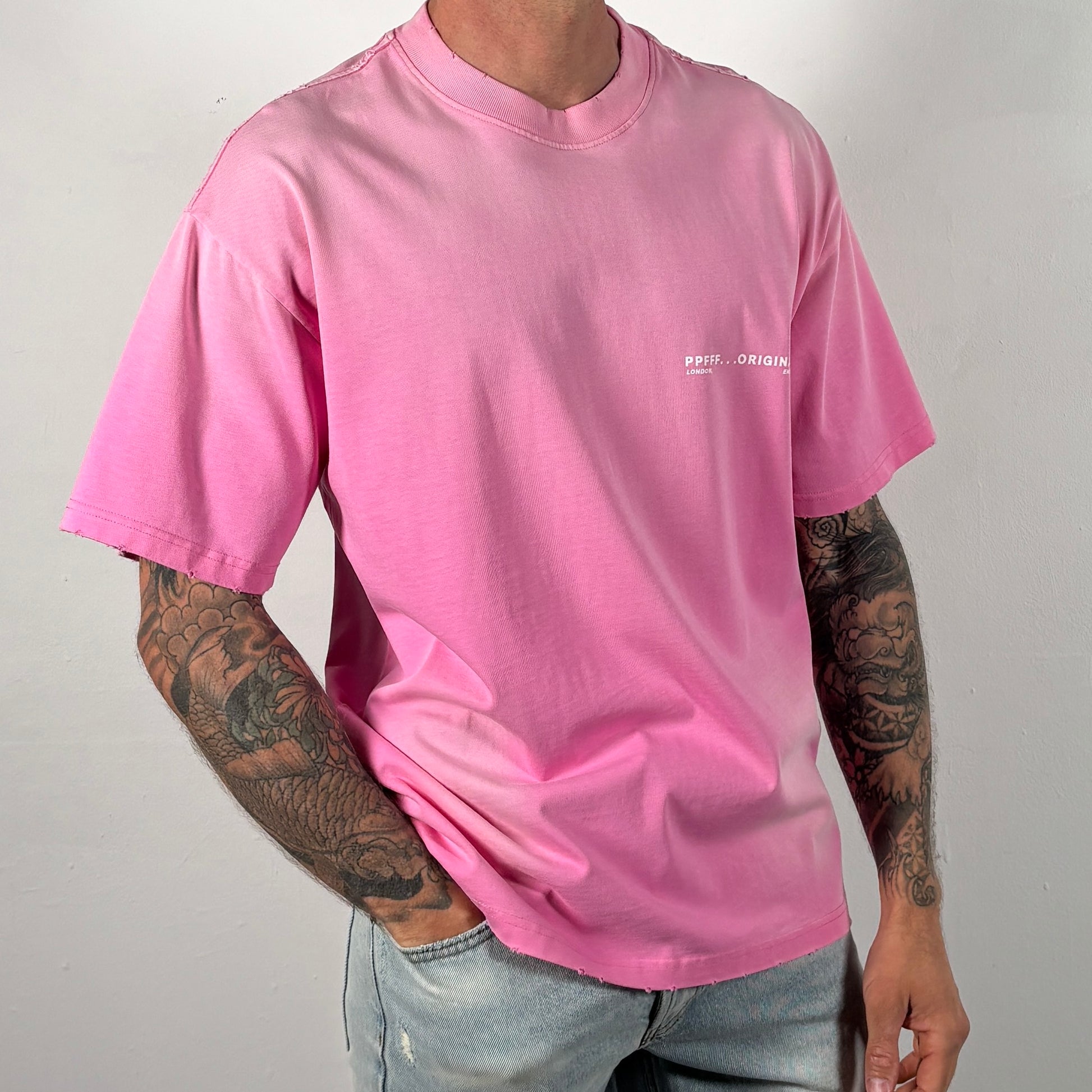 Person wearing a pink t-shirt with a logo on a plain background