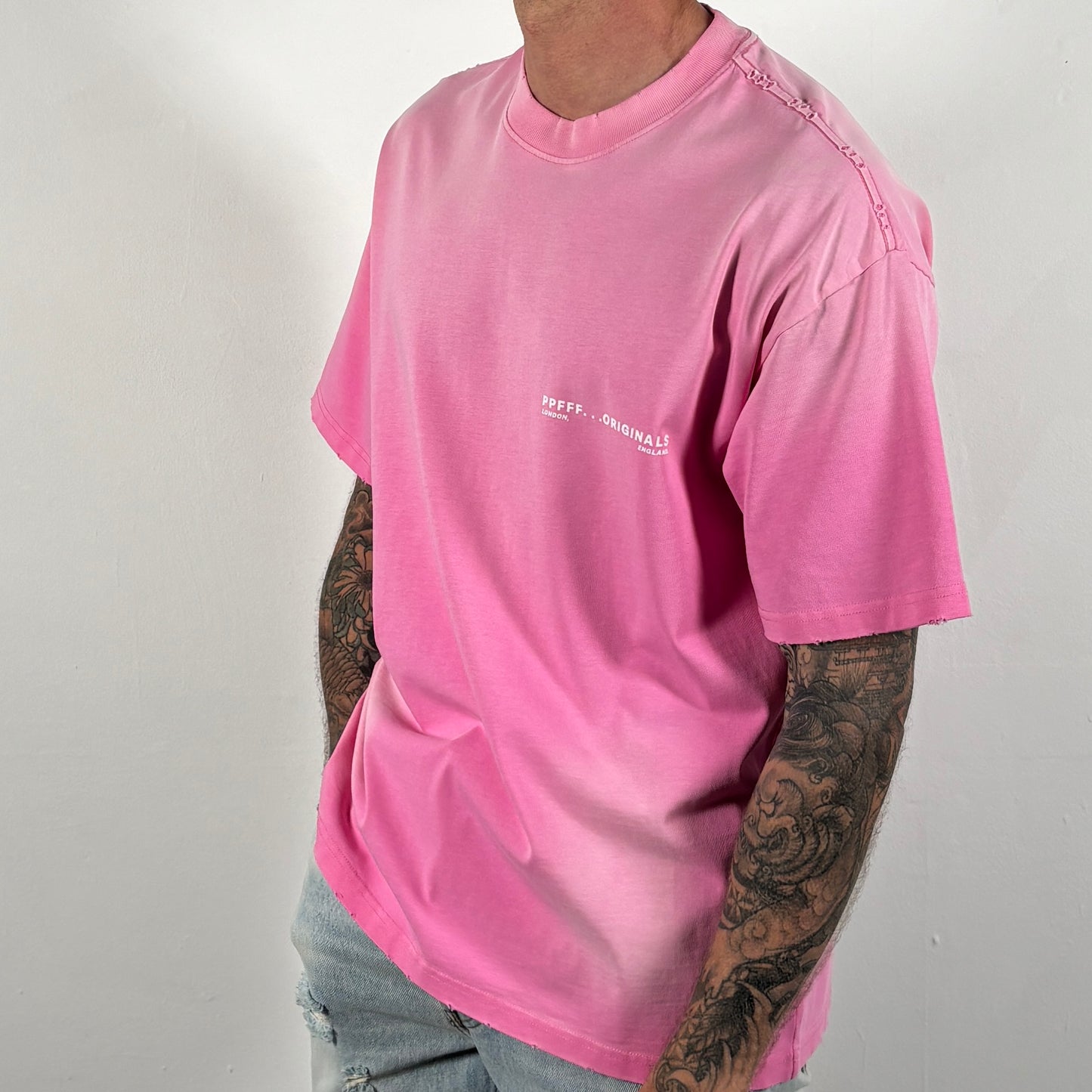 Person wearing a pink t-shirt with text on a plain background
