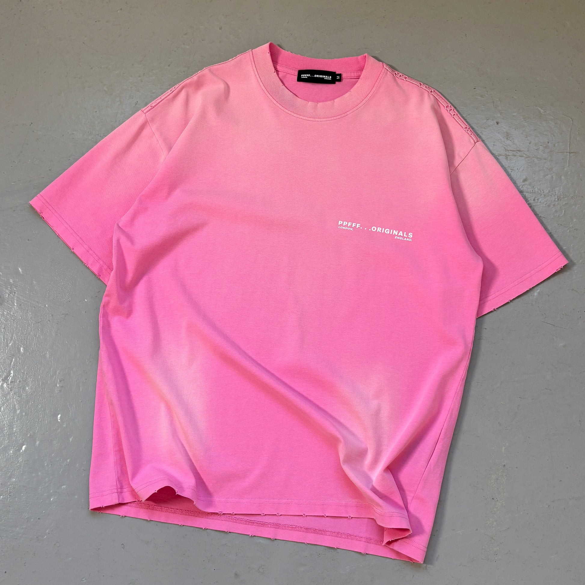Pink t-shirt with text on a gray surface