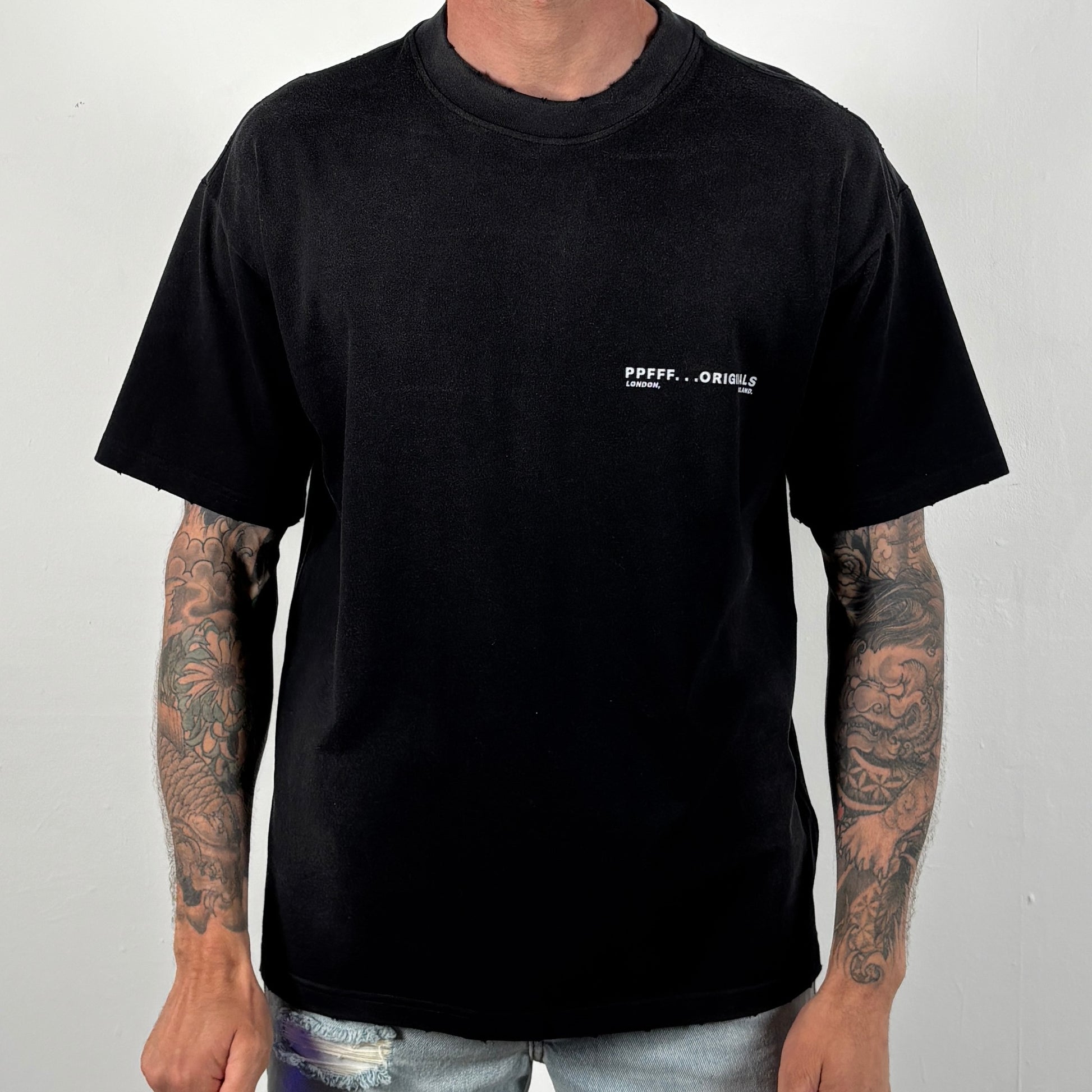 Person wearing a black t-shirt with a logo on a plain background