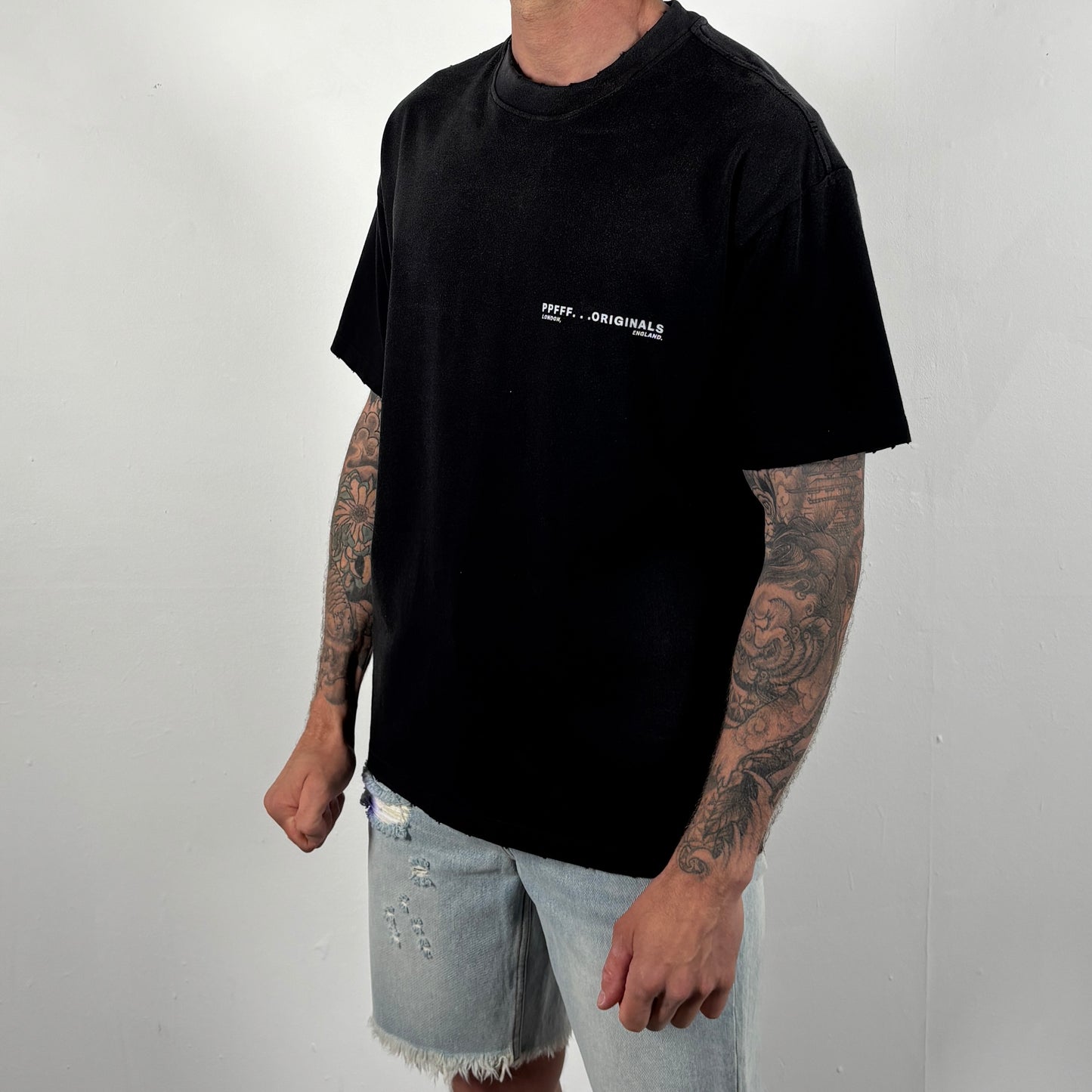 Person wearing a black t-shirt with a logo on a plain background